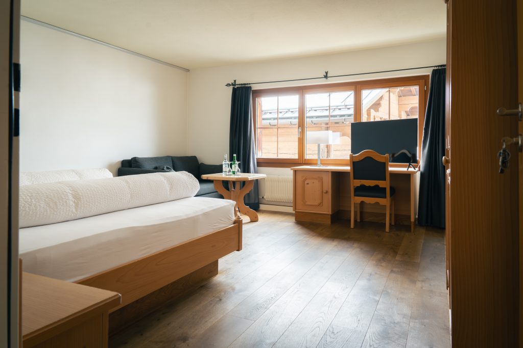 Spacious Superior double room at Hotel Alpina Brigels with double bed, desk, TV, and sofa