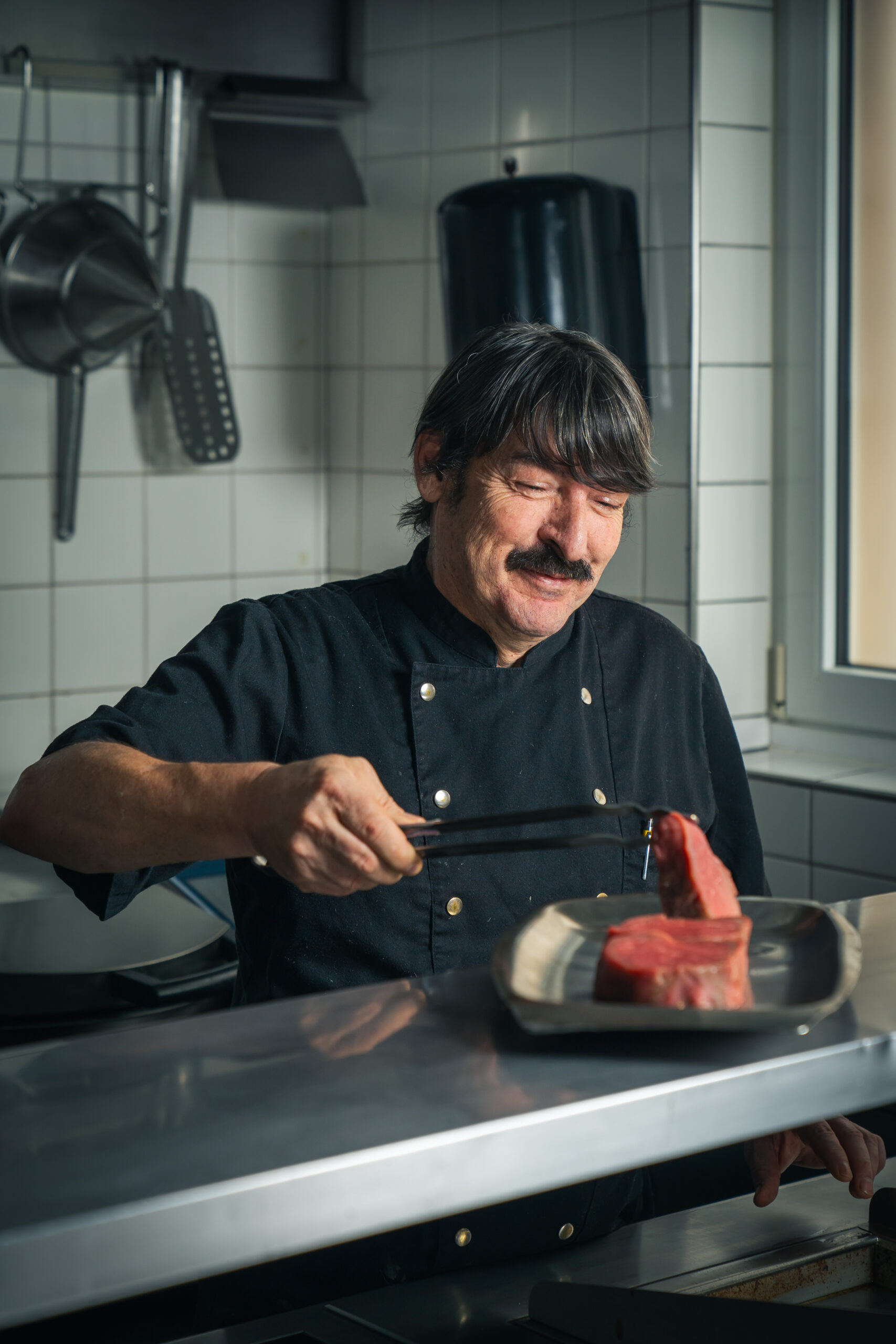 Gerold Chef from Alpina Brigels in the kitchen searing a piece of meat
