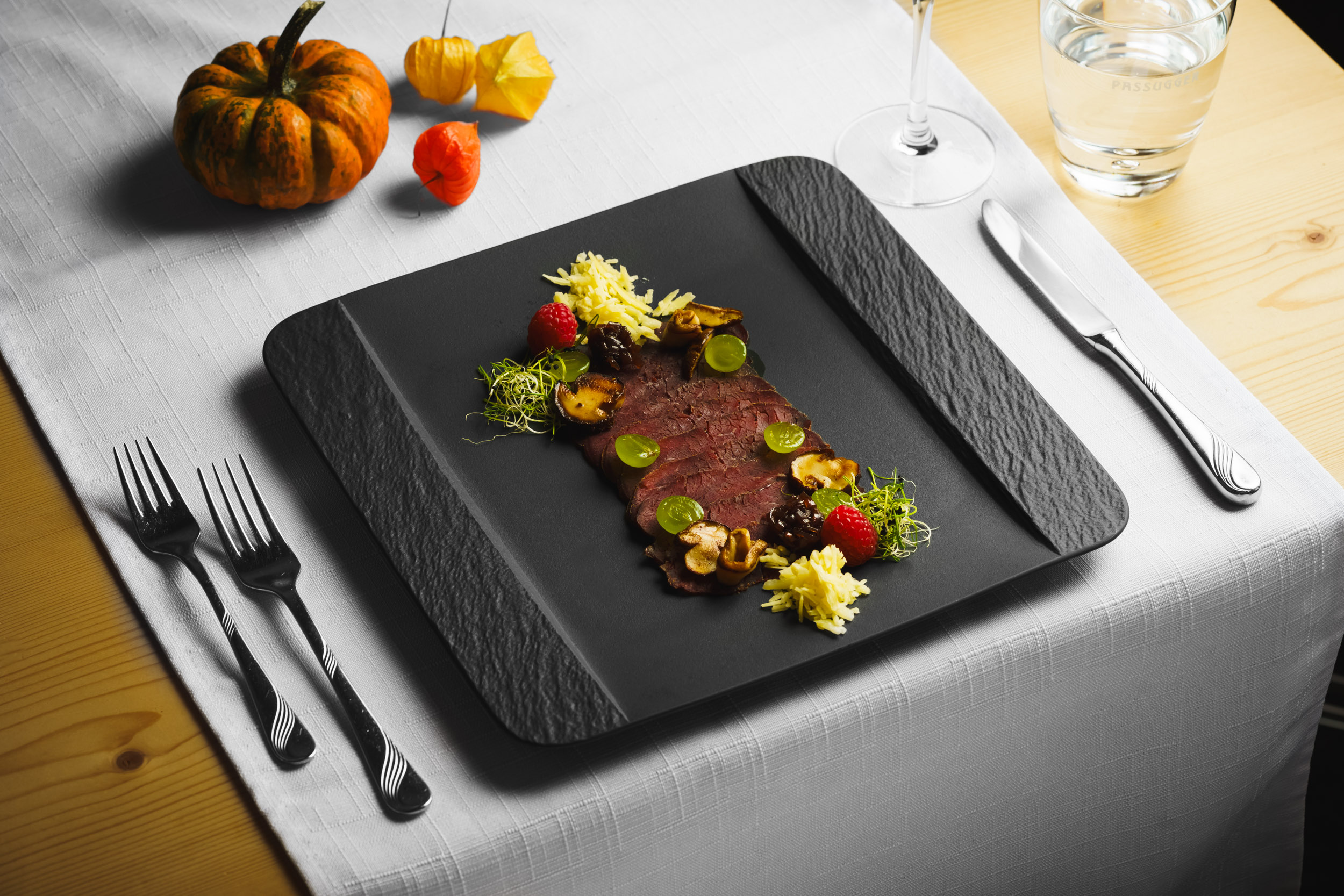 Restaurant dish: Venison carpaccio "Alpina style," served on a black plate beautifully garnished