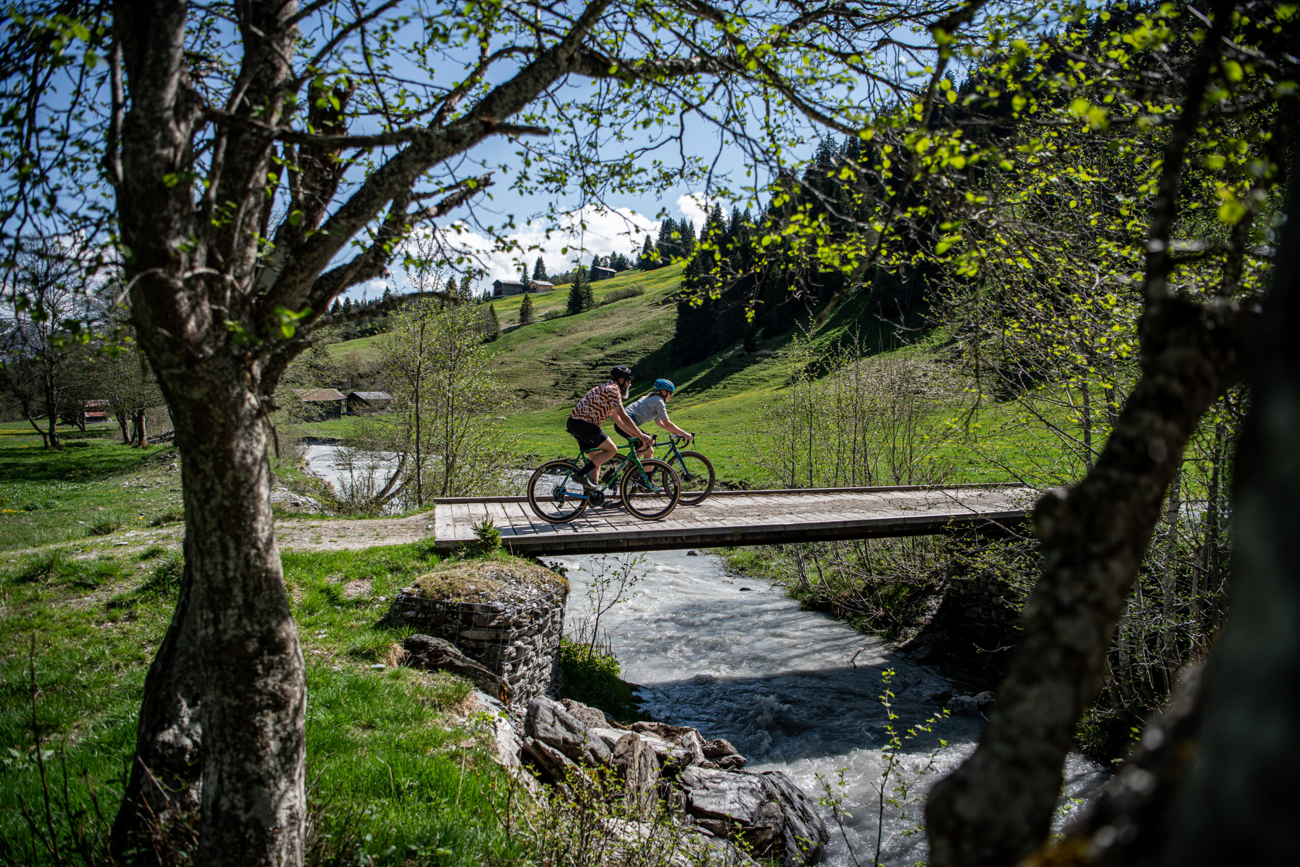 Two people riding gravel bikes on a bridge in Brigels